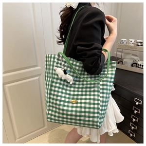 Detail of green plaid canvas tote bag with metal handmade tag and cute puppy plush charm