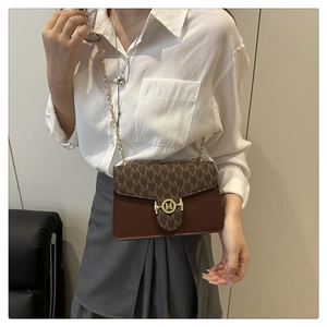 Chic brown monogram crossbody bag with golden chain strap shown on model in white shirt