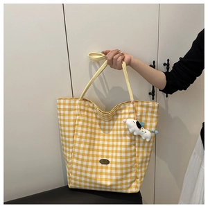 Detail van de gele geruite canvas tas met handgemaakte patch en pluche hanger
