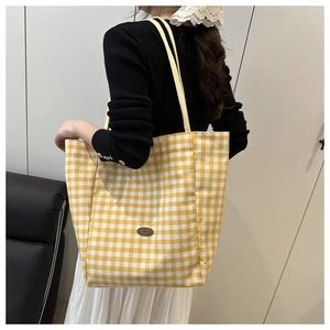 Detail of yellow gingham canvas tote bag with long shoulder straps and brand logo