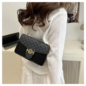 Detail of grey monogram crossbody bag with gold M-lock and metal chain strap on model