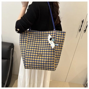 Detail van geel-blauw geblokte canvas shopper met schattige witte hondenknuffel hanger