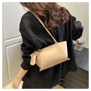 Detailed view of the beige leather tote bag's stitching and slim shoulder strap