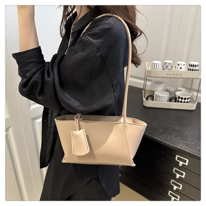 Minimalist beige trapezoid underarm bag worn by a model in a modern professional setting