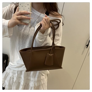Détails du sac sous le bras en cuir marron avec surpiqûres en V et étiquette en cuir