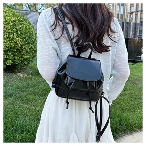 Outdoor shot of a black mini PU leather backpack with mini embossed flap and drawstring