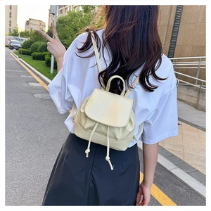 Detail of cream white mini PU leather backpack featuring flap design and drawstring accents