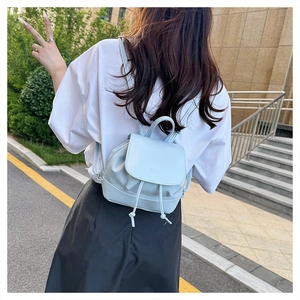 Detail of light blue mini leather backpack with drawstring closure worn by a model