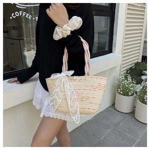 Detail of beige woven straw bag with colorful stripes and a delicate white lace bow