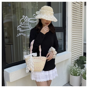 Close-up of woven straw hat and tote bag with delicate white lace and pearl accents