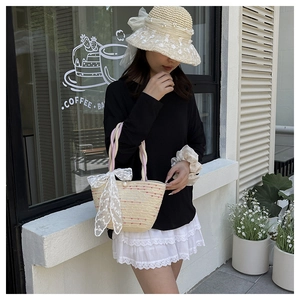 Detailed straw beach bag featuring delicate embroidery lace bow and pearl button accent