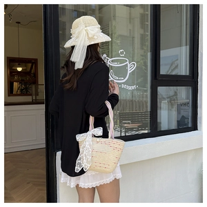 Detail of straw woven tote bag with red dots, lace bow and matching sun hat for beach