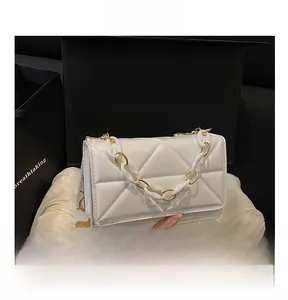 Close-up of white quilted square bag with gold chain and jacquard wide strap details