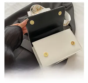 Detail of white leather flap bag showing premium gold magnetic closures and wide strap