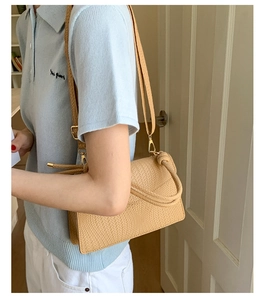 Détail du sac à main beige tressé avec ferrures dorées et poignée nouée élégante