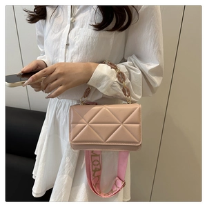 Detail of pink crossbody bag with geometric pattern and amber chain strap shown on model
