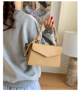 Détail du sac à main beige tressé avec poignée nouée et anneaux métalliques chic