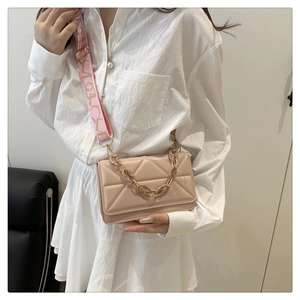 Detail of pink quilted crossbody bag with LOVE strap and resin chain on model