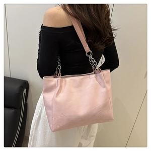 Detail of pink geometric quilted tote bag with metal chain strap worn by a model