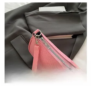 Close-up of silver metal zipper and embossed faux leather texture on pink shoulder bag