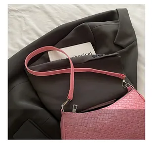 Detail of pink woven leather shoulder bag showing texture on a grey blazer