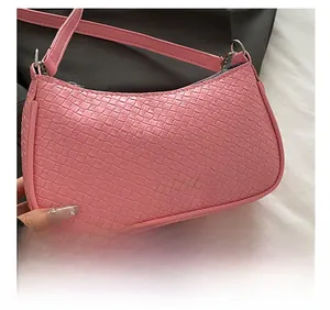 Close-up of pink woven PU leather shoulder bag with metallic buckle and zipper