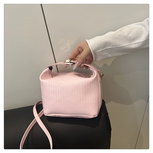 Detail view of pink textured box bag with metallic lock and adjustable shoulder strap