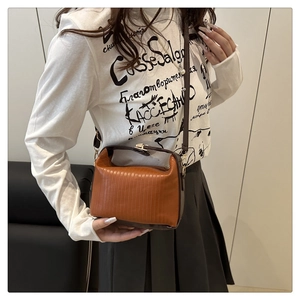 Detail of vintage contrast stitching and metal clasp on brown crossbody pillow bag