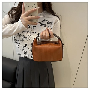 Detailed view of brown pleated texture and zipper closure on a faux leather handbag