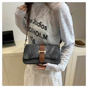 Détail du sac bandoulière gris foncé avec lanières en cuir marron et fermoir en H doré