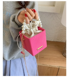Detail of pink cube bucket bag featuring woven texture and large faux pearl top handle