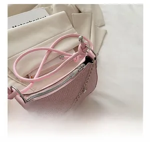Détail du sac sous le bras rose tressé avec chaîne argentée et fermeture éclair fluide