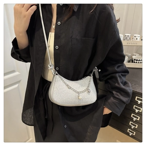 Détail du sac bandoulière argenté en demi-lune avec chaîne perlée et cœur