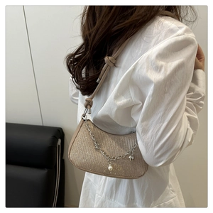 Détail du sac sous le bras pailleté champagne avec breloques cœur et bandoulière nouée