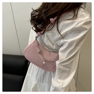 Sac baguette rose scintillant avec chaîne argentée et perle sur l'épaule d'une femme