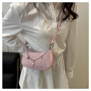 Détail du sac demi-lune rose à paillettes avec chaîne argentée et perle sur modèle