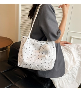 Detail of white tote bag featuring black bow patterns, pleated texture and cloud charm