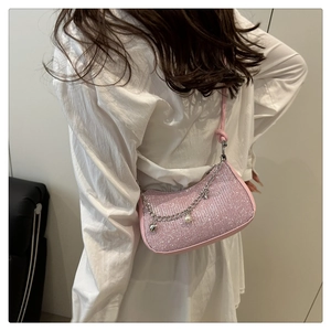 Detail of pink sequin underarm bag featuring heart charms and pearl chain on a shoulder bag