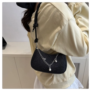 Détail du sac à bandoulière à paillettes noires avec breloques étoiles et cœurs argentés