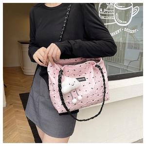 Pink quilted tote bag with black bows and plush cloud charm worn by a model
