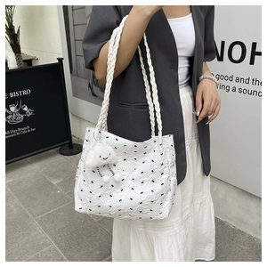 White quilted tote bag with bow prints and cloud charm shown in an outdoor street style