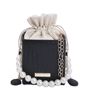 Chic black woven bucket bag with pearl handle, drawstring liner, and golden chain strap