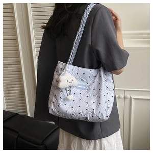 Detail of light blue quilted tote bag with black bow print and smiley cloud charm