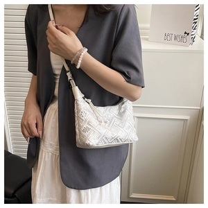 Detail of ethnic pattern on beige underarm tote bag with refined bead strap knot