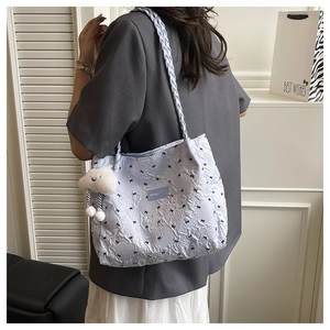 Detail of light blue quilted tote bag with black bows and white cloud plush charm