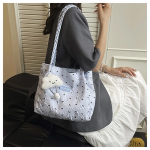 Detail of light blue quilted tote bag with black bow prints and braided shoulder strap