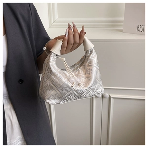 Detailed close-up of geometric pattern embroidery and bead charms on silver tote bag