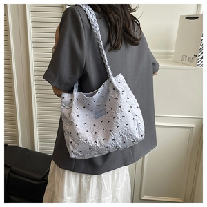 Quilted tote bag detail featuring bow embroidery and braided shoulder strap