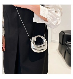 Mini silver crescent moon bag with metallic chain strap worn over minimalist outfit