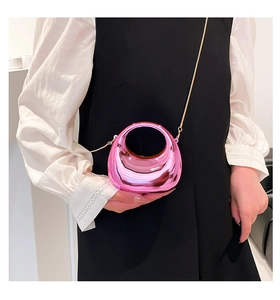 Close-up of metallic pink half-moon box bag with gold chain strap on a black outfit